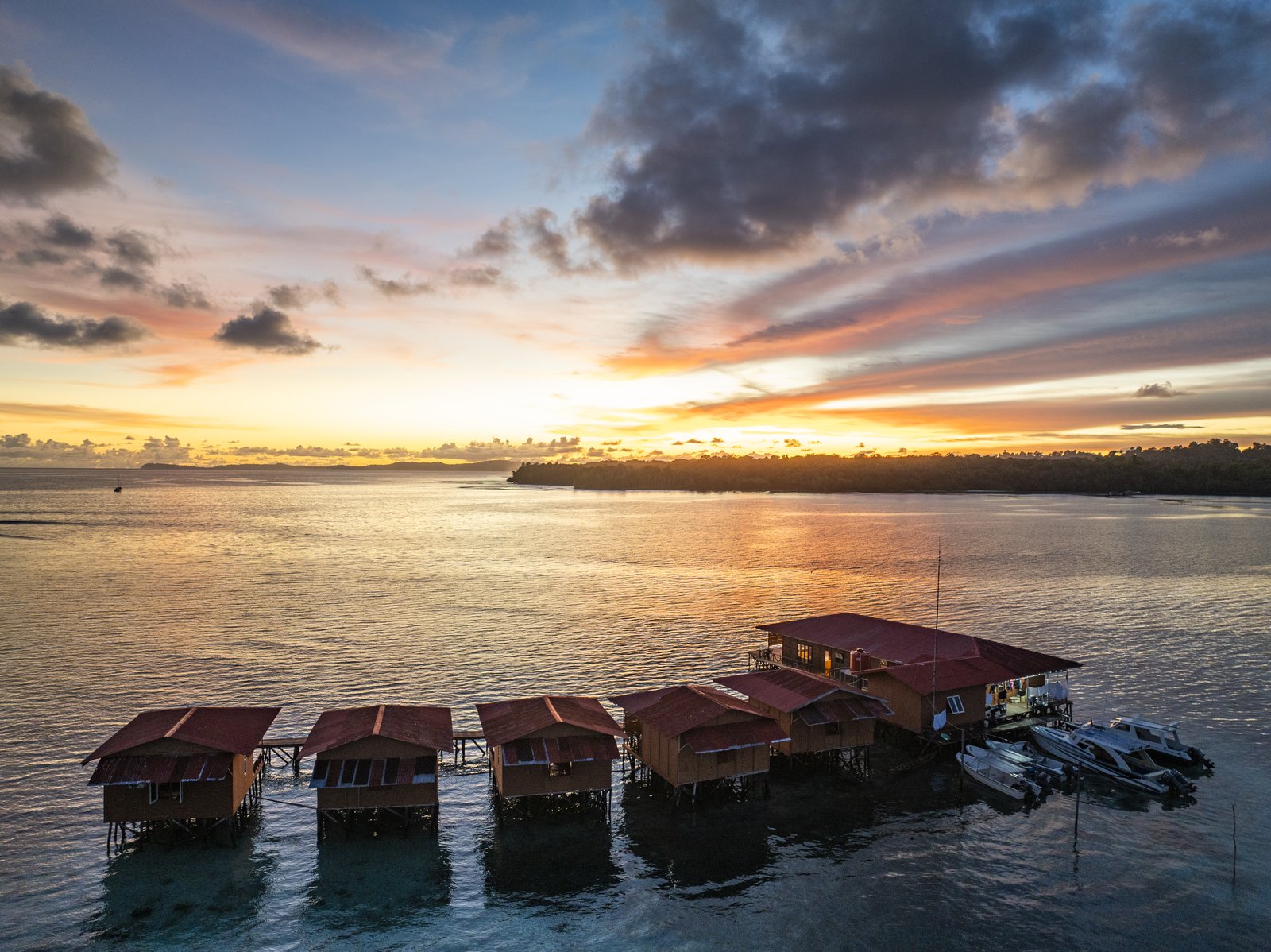 The whole overwater property at sunset, photographed from a drone