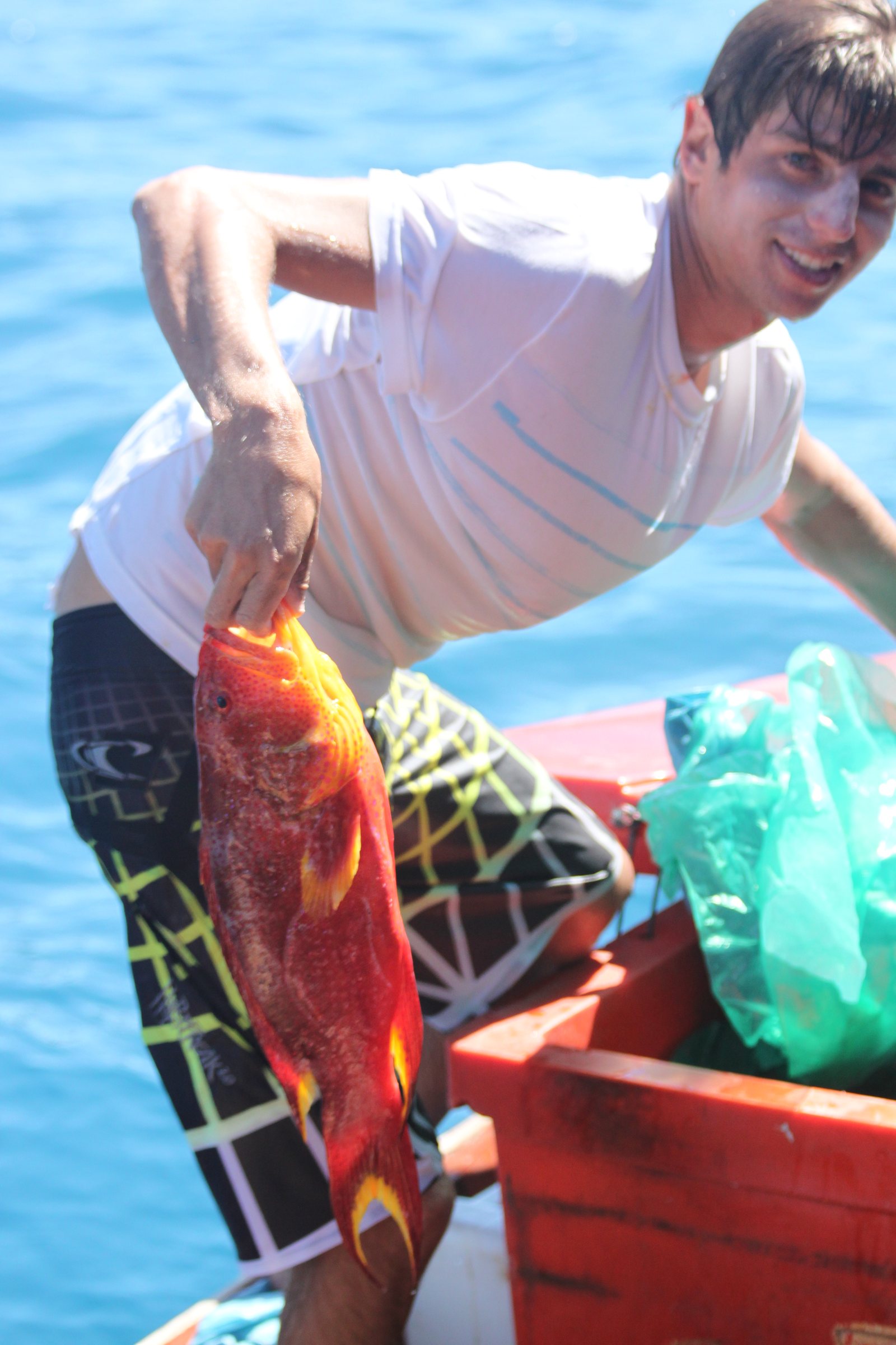 A guest holding a red fish aboard the boat