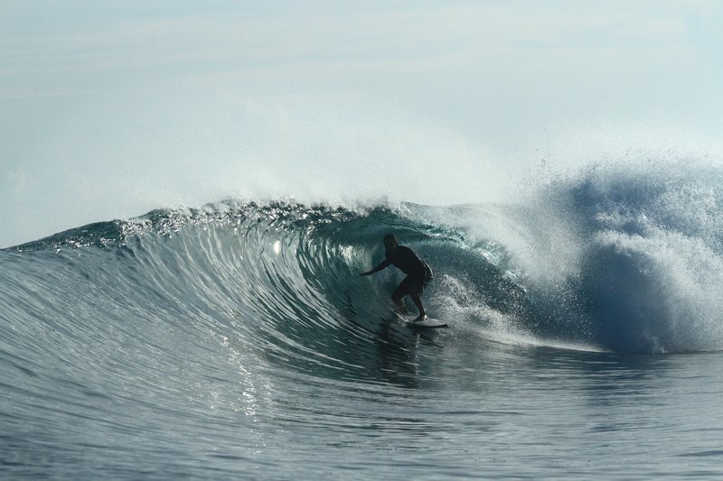 Lizard Nest: A surfer riding a wave in the Banyak Islands