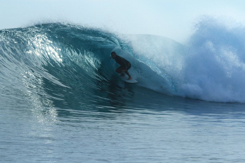 Lizard Nest: A surfer riding a wave in the Banyak Islands