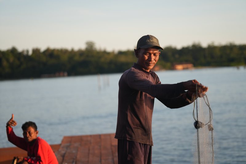 A fisherman tending his net beside the villas