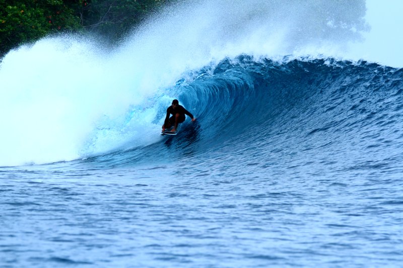 Lolok Point: A surfer on a breaking wave in the Banyak Islands